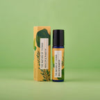 Blaue 10-ml-Glasflasche mit Roll-On-Kufsatz und goldgelbem Etikett sowie daneben stehender Umverpackung vor hellgrünem Hintergrund.