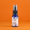 Blaue 20ml-Sprühflasche mit schwarzem Pumpkopf und einem Etikett mit der Aufschrift „The Nature of Things Lavender Pillow Mist“ vor orangefarbenem Hintergrund.