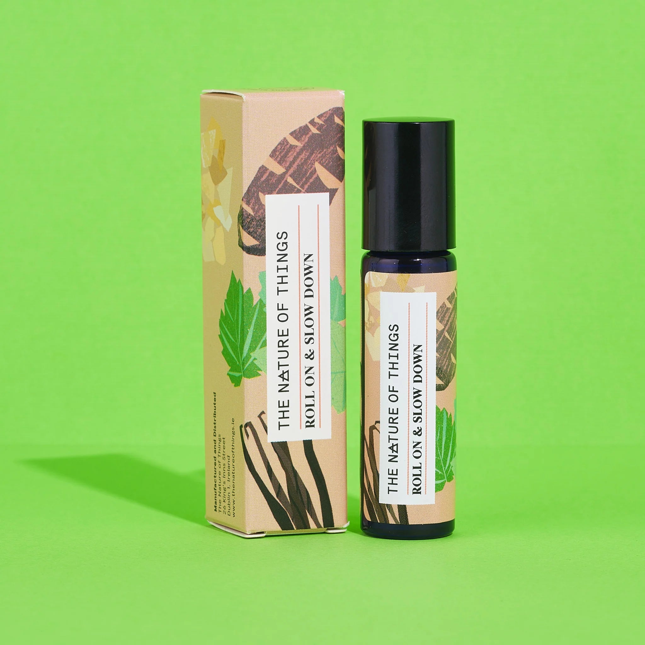 Blauer 10-ml-Roll-On und dazugehörige beige Umverpackung mit Vanille- und Blätter-Illustrationen vor einem grünen Hintergrund.
