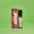 Blauer 10-ml-Roll-On und dazugehörige pinke Umverpackung mit Orangen- und Blatt-Illustrationen vor einem grünen Hintergrund.
