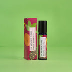 Blauer 10-ml-Roll-On und dazugehörige pinke Umverpackung mit Orangen- und Blatt-Illustrationen vor einem grünen Hintergrund.