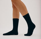 Schwarze Core Crew Socks in klassischer Crew-Länge an den Beinen eines Modells vor hellem Hintergrund.