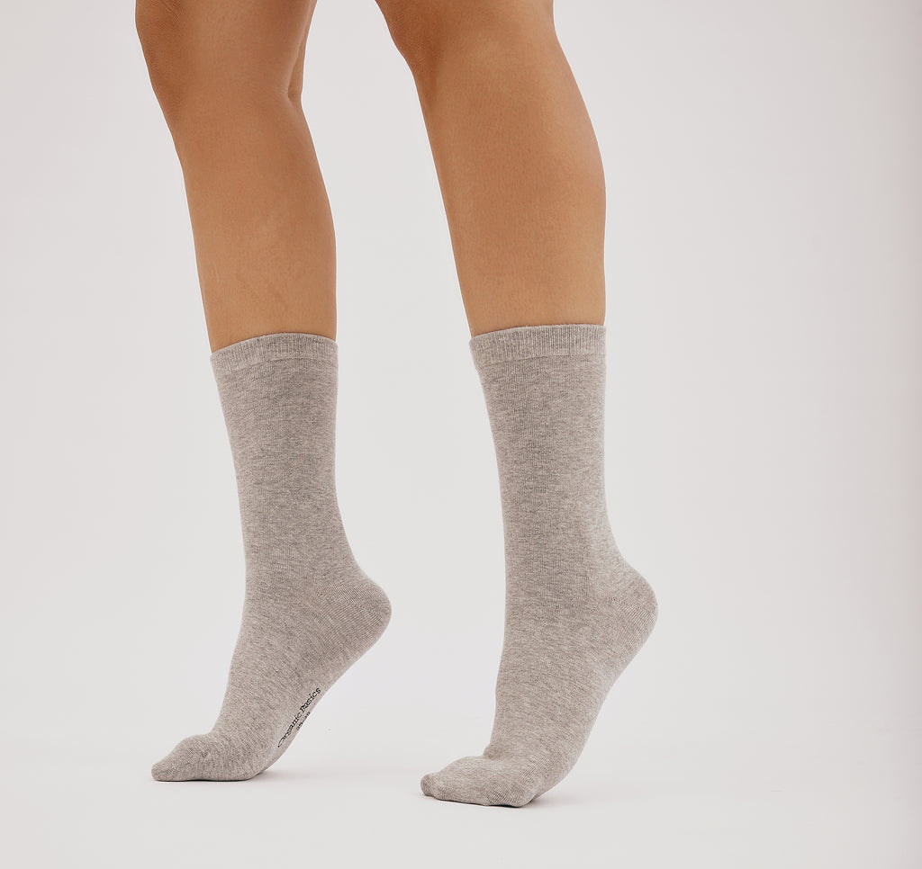 graue Core Crew Socks in klassischer Crew-Länge an den Beinen eines Modells vor hellem Hintergrund.