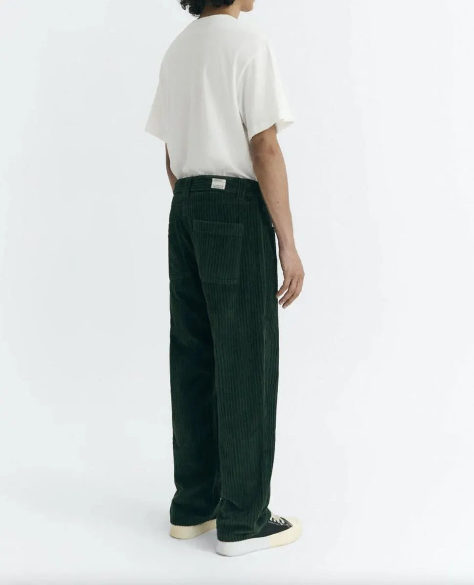 Dunkelgrüne Cordhose "David" von Thinking Mu aus feinem Cord-Stoff mit klassischen Taschen und Gürtelschlaufen vor hellem Hintergrund.