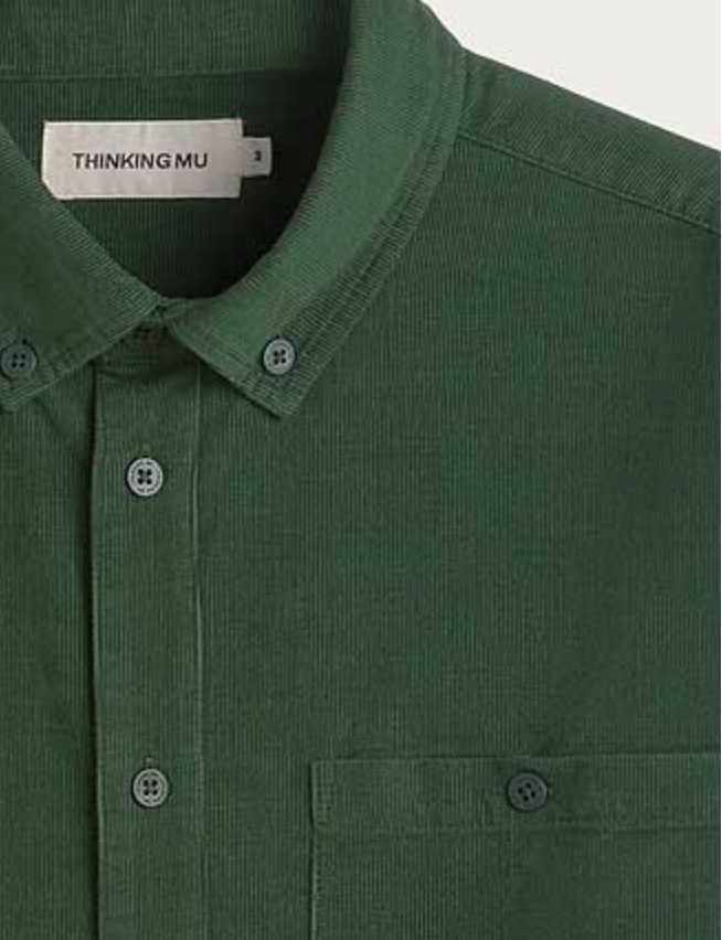 Dunkelgrünes Microcord-Hemd "Anto" von Thinking Mu mit Button-Down-Kragen, Knopfleiste und Brusttasche vor hellem Hintergrund.