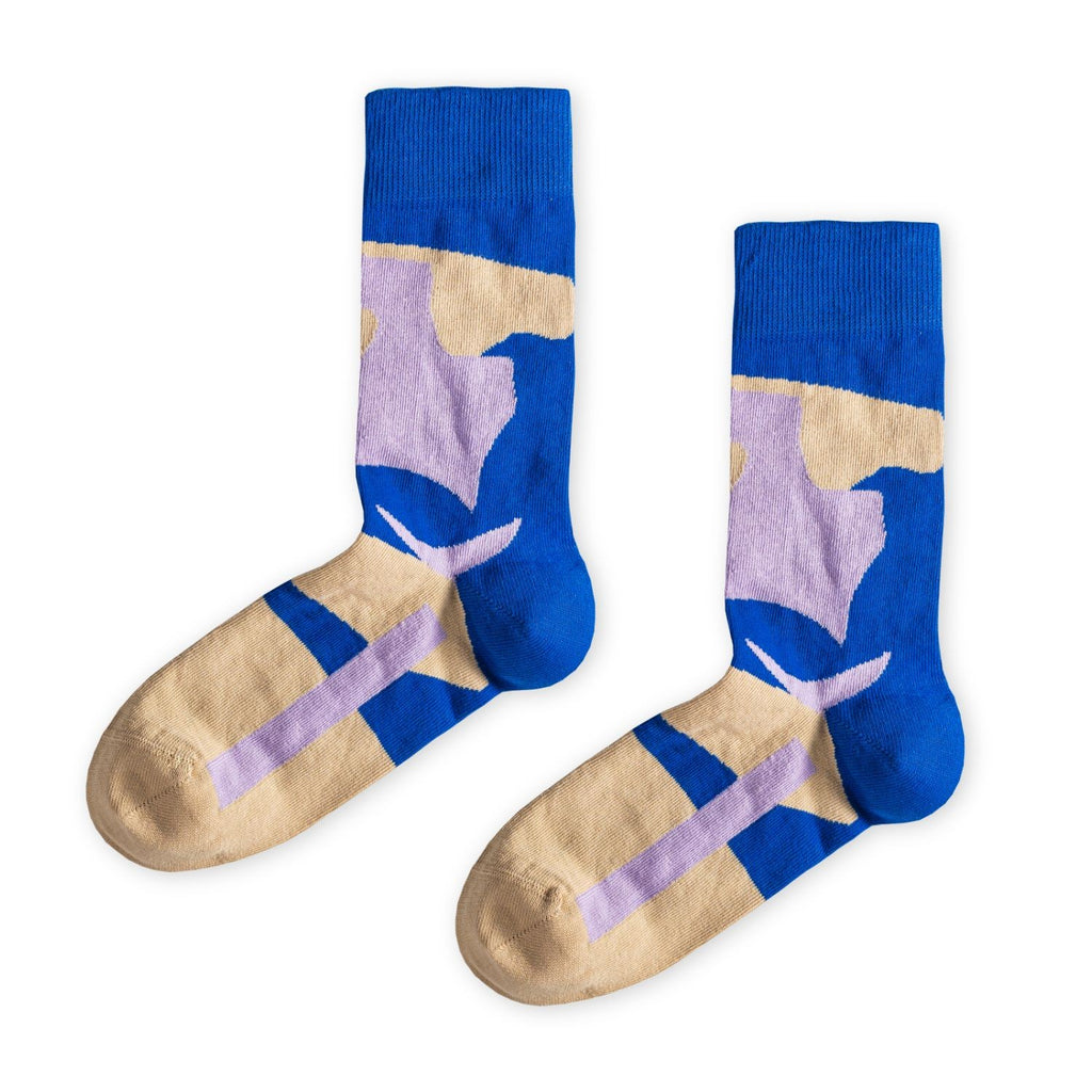 Ein Paar blaue Socken mit beigen und violetten, abstrakten Farb- und Blockmustern sowie beiger Fersen- und Zehenpartie vor hellem Hintergrund. koblenz