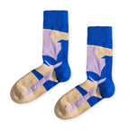 Ein Paar blaue Socken mit beigen und violetten, abstrakten Farb- und Blockmustern sowie beiger Fersen- und Zehenpartie vor hellem Hintergrund. koblenz