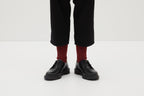 Ein Paar gestrickte Socken aus Wolle in meliertem Rot vor weißem Hintergrund. seide