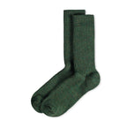 Ein Paar gestrickte Socken aus Wolle in meliertem Waldgrün vor weißem Hintergrund.