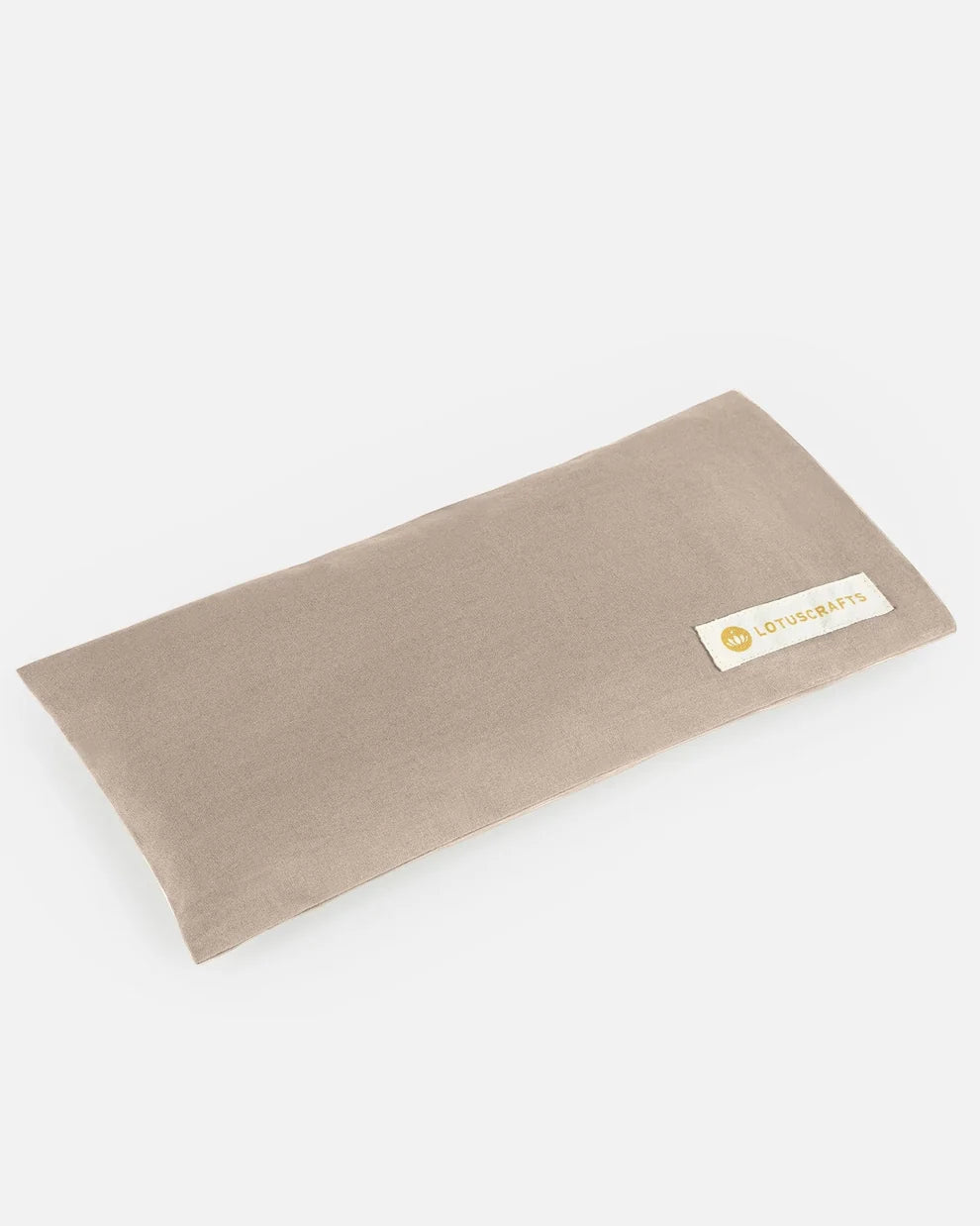 Ein beige-graues Augenkissen aus Bio-Baumwolle mit aufgenähtem Lotuscrafts-Logo-Etikett vor hellem Hintergrund.