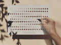 Ein cremefarbener DIN A4 Adventskalender von Anna Cosma im Querformat mit Mondphasen-Muster und dem Zitat „Nothing changes if nothing changes“ sowie geöffnetem Türchen.