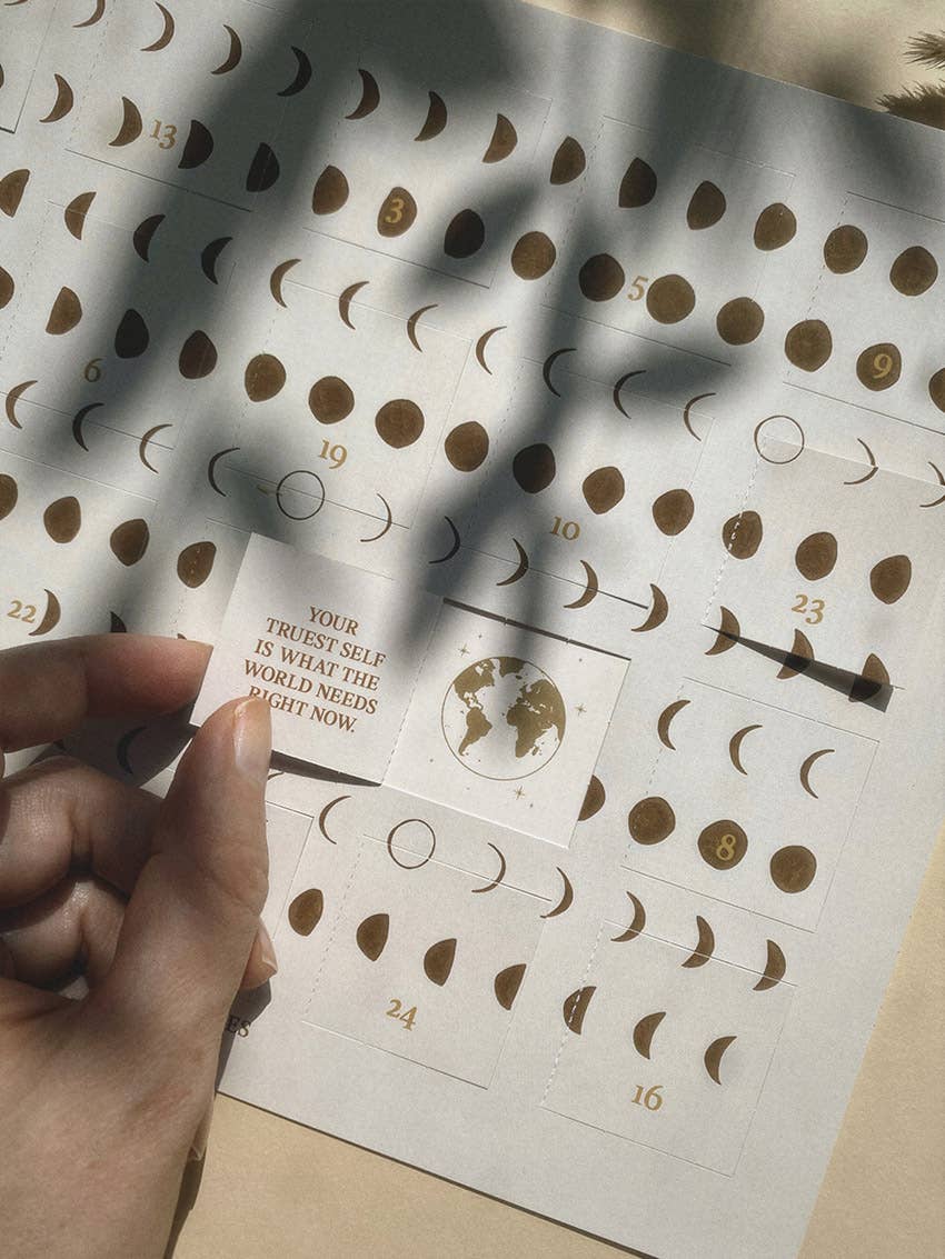 Ein cremefarbener DIN A4 Adventskalender von Anna Cosma im Querformat mit Mondphasen-Muster und dem Zitat „Nothing changes if nothing changes“ sowie geöffnetem Türchen. koblenz trust concept store
