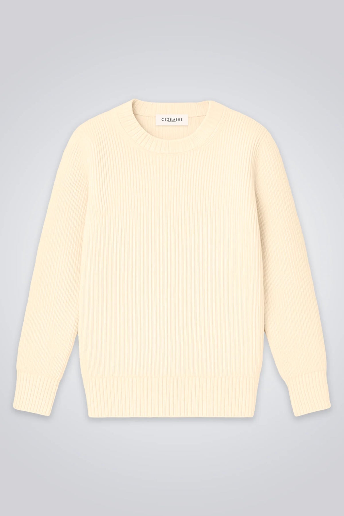 Ein klassischer Wollpullover in hellem Ecru mit feiner Rippstruktur und Rundhalsausschnitt auf hellem Hintergrund.