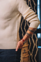 Ein klassischer Wollpullover in hellem Ecru mit feiner Rippstruktur und Rundhalsausschnitt auf hellem Hintergrund.