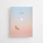 Eine Postkarte mit Rosé-Blau-Farbverlauf, Sonne und fliegendem Greifvogel sowie dem Schriftzug FOCUS ON THE GOOD.
