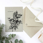 Eine Weihnachtskarte aus naturbelassenem Graspapier mit handgezeichnetem Stechpalmenzweig und dem Schriftzug „OH DU FRÖHLICHE!“ 