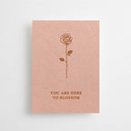 Eine altrosafarbene Mini-Karte mit einer feinen Rosen-Illustration und dem englischen Schriftzug „YOU ARE HERE TO BLOSSOM“ vor weißem Hintergrund.
