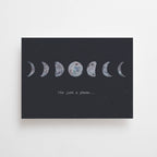 Eine dunkelgraue Postkarte von Anna Cosma im Querformat mit illustrierten Mondphasen und der englischen Aufschrift „It's just a phase...“.