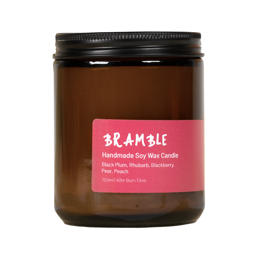 Eine handgefertigte Och Vegan Sojawachskerze im braunen Apothekerglas mit schwarzem Schraubdeckel und einem dunkelrosafarbenen Etikett mit der Aufschrift „BRAMBLE Handmade Soy Wax Candle“ 