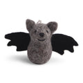 Eine kleine, graue Filz-Fledermaus mit schwarzen Flügeln und gesticktem Gesicht, aufgehängt an einer Kordel vor hellem Hintergrund.