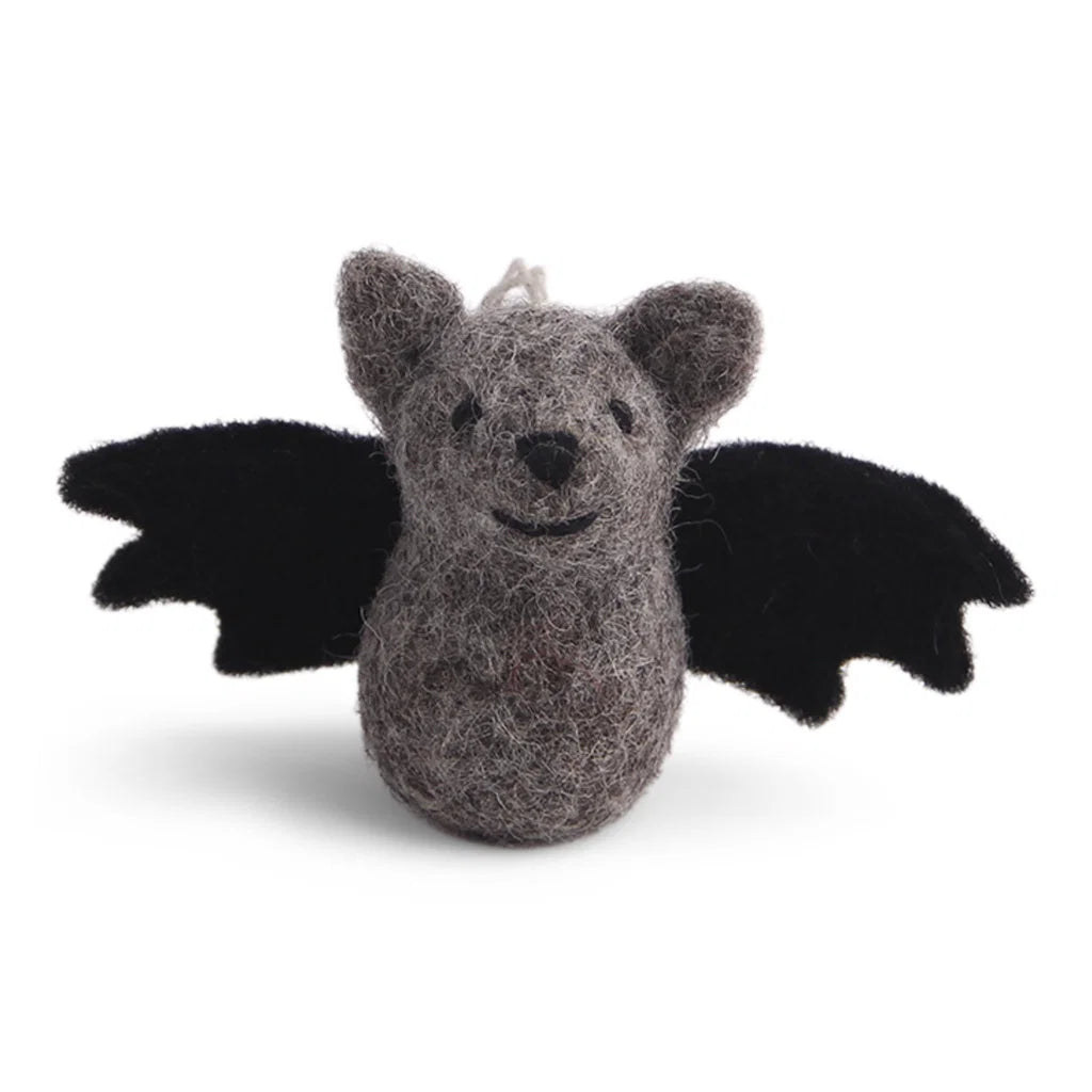 Eine kleine, graue Filz-Fledermaus mit schwarzen Flügeln und gesticktem Gesicht, aufgehängt an einer Kordel vor hellem Hintergrund.
