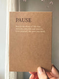 Eine minimalistische Postkarte im warmen Sand-Farbton mit dem Schriftzug PAUSE und einem englischen Zitat über die Kraft der Ruhe.