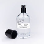 Flaura Parfumflasche mit dekorativen Vanilleschoten und Zimtstangen.