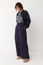 Frontansicht der dunkelblauen HALTSU Jacke an einem Modell kombiniert mit einer weiten Hose.