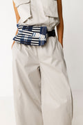 Tragebeispiel der ADOR BAG Gürteltasche in Blau-Weiß an der Taille eines Modells in einem hellen Jumpsuit.