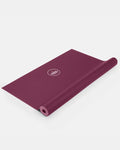 Gefaltete weinrote Yogamatte "Arise Travel" in Dark Cranberry mit Lotus-Logo vor hellem Hintergrund.