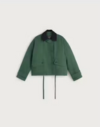 Grüne Jacke "Norma" von Thinking Mu mit dunklem Cord-Kragen, Knöpfen und herabhängenden Bändern am Saum vor hellem Hintergrund.