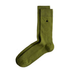 Grüne Socken Luji im Rippstrick-Design mit nahtloser Fußspitze, abgebildet als flach liegendes Produkt und getragen mit schwarzen Schuhen.