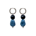 in Paar handgefertigte Keramikohrringe Fortuna Hoop mit silbernen Edelstahl-Ringen, einer schwarzen runden Perle und einer größeren, marmorierten blauen Keramikperle.