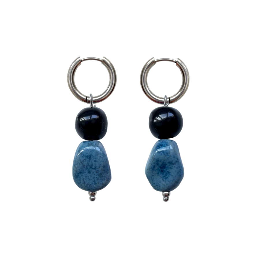 in Paar handgefertigte Keramikohrringe Fortuna Hoop mit silbernen Edelstahl-Ringen, einer schwarzen runden Perle und einer größeren, marmorierten blauen Keramikperle.
