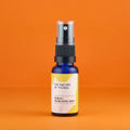 Kleine blaue 20ml-Sprühflasche des Neroli Mists von The Nature of Things mit gelb-weißem Etikett und durchsichtigem Sprühkopf auf orangefarbenem Hintergrund.