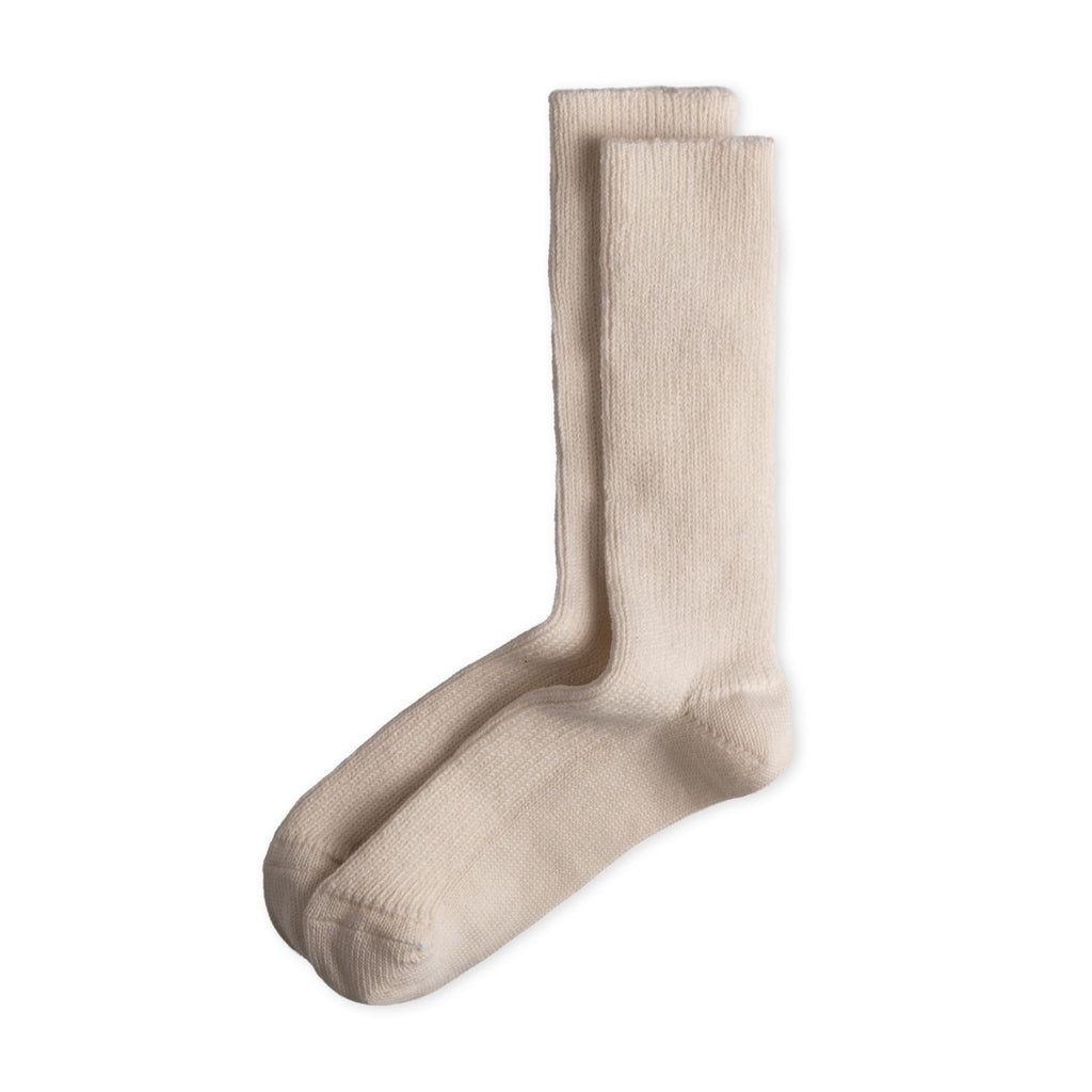 Ein Paar gestrickte Socken aus Wolle in meliertem Cremeweiß vor weißem Hintergrund.