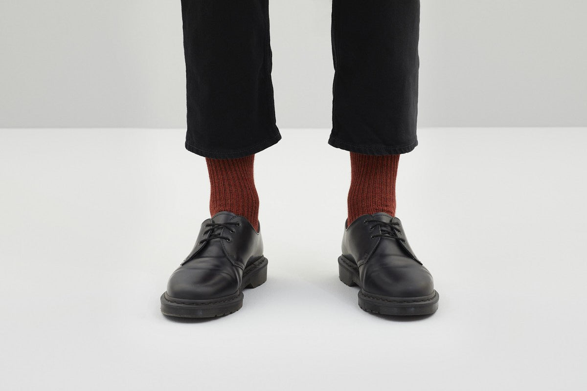 Koblenz; Ein Paar dicke, rustikal gestrickte Socken in Rostrot mit einem gerippten Bündchen. 