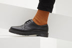 Koblenz Ein Paar gestrickte Socken aus Wolle in meliertem Rostorange vor weißem Hintergrund.