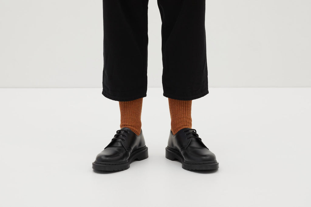 Koblenz Ein Paar gestrickte Socken aus Wolle in meliertem Rostorange vor weißem Hintergrund. ferdinand