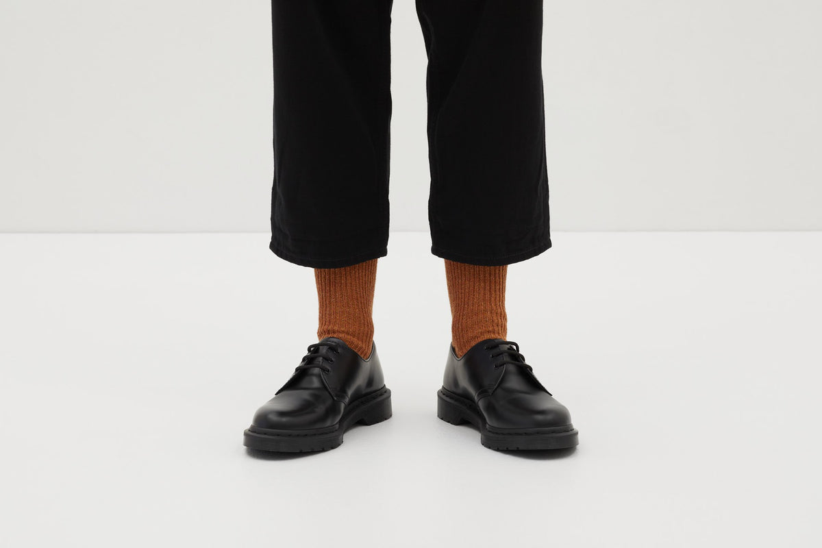 Koblenz Ein Paar gestrickte Socken aus Wolle in meliertem Rostorange vor weißem Hintergrund. ferdinand