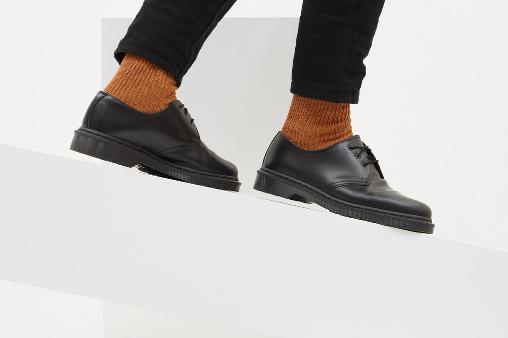 Koblenz Ein Paar gestrickte Socken aus Wolle in meliertem Rostorange vor weißem Hintergrund. ferdinand trust