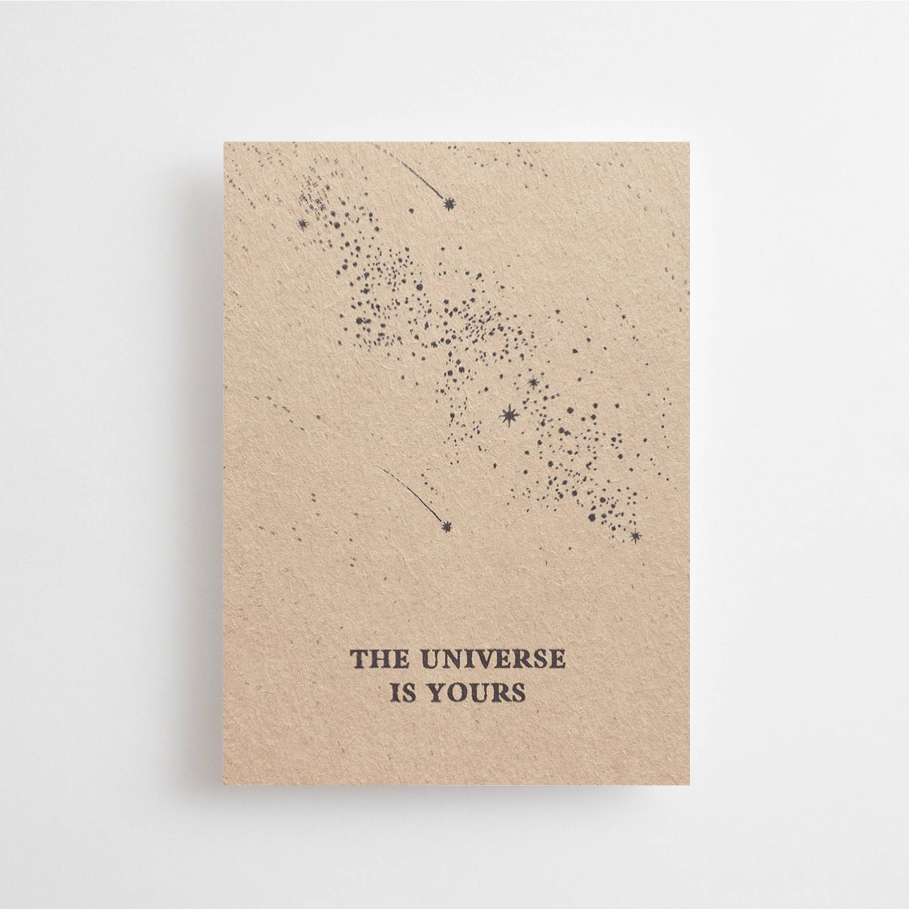 Mini-Postkarte „The Universe is Yours“ im DIN-A7-Format mit einer sternenreichen Galaxie-Illustration auf braunem Naturpapier vor hellem Hintergrund.
