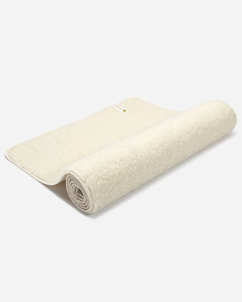 Natürliche, cremeweiße Schurwolltagematte "WOOL" mit dichtem Hochflor im Hochformat vor hellem Hintergrund.