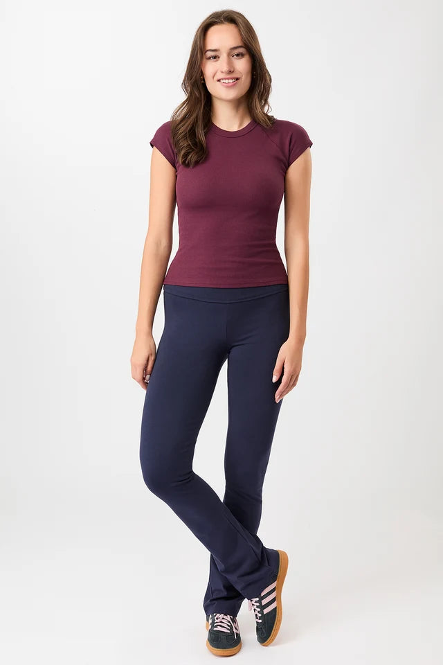 Person von vorne in einem dunkelroten, gerippten Slim-Fit-T-Shirt mit kurzen Ärmeln und Raglanschnitt vor hellem Hintergrund.