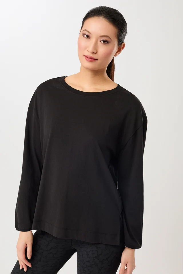 Person von vorne in einem schwarzen, oversized Langarmshirt "Wide" mit rundem Ausschnitt vor hellem Hintergrund.