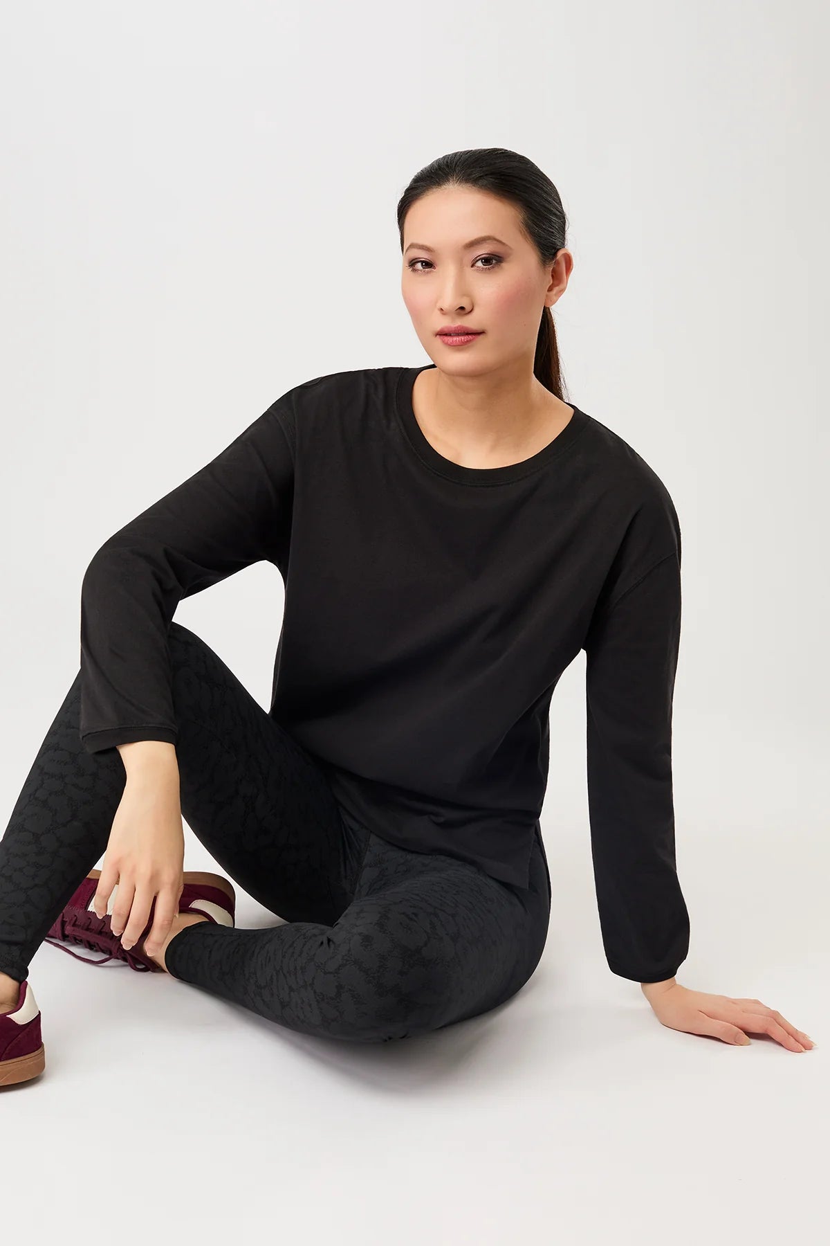 Person von vorne in einem schwarzen, oversized Langarmshirt "Wide" mit rundem Ausschnitt vor hellem Hintergrund.