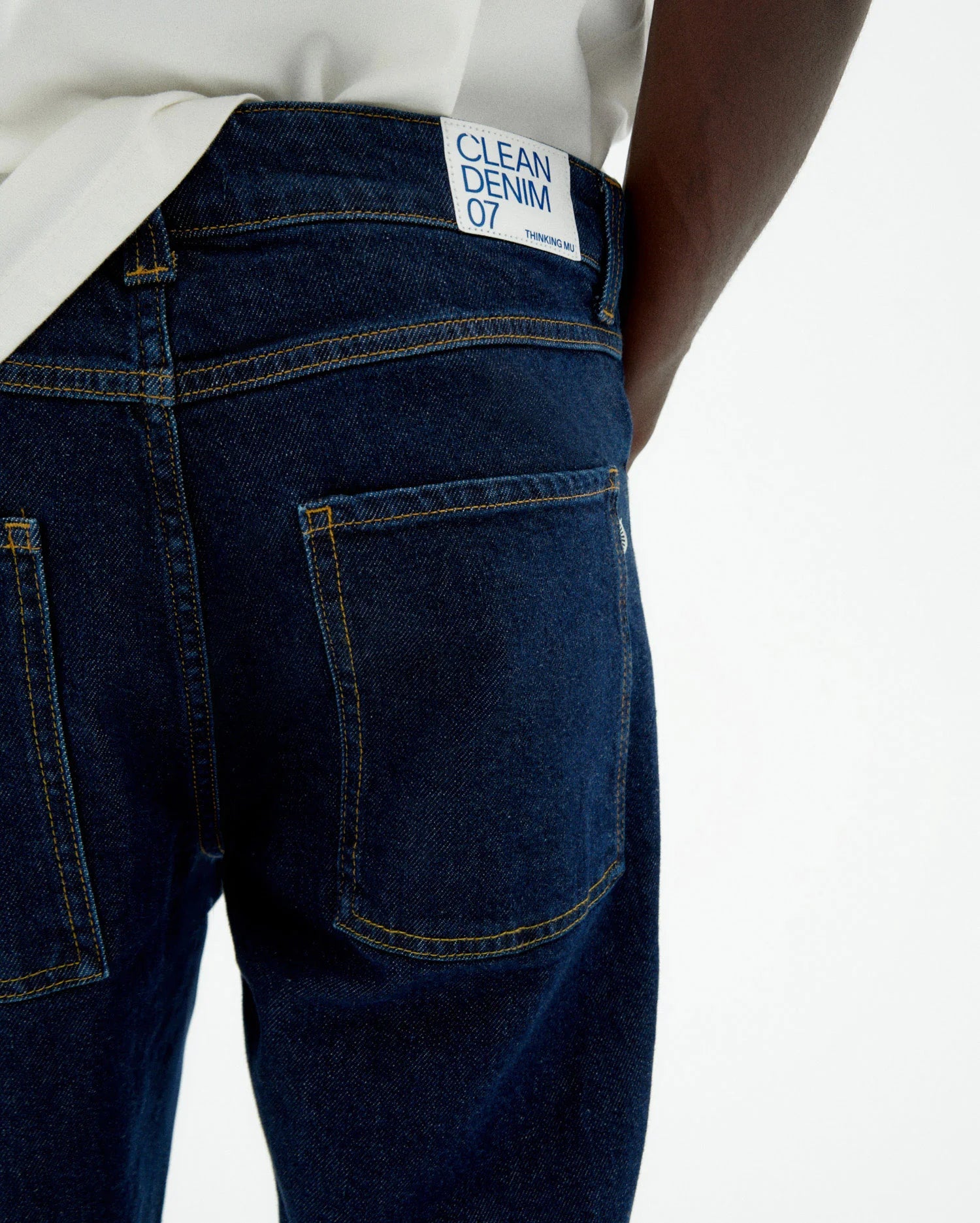 Person von vorne in einer dunklen Straight-Leg Jeans "David" mit hellem Shirt und braunen Schuhen vor hellem Hintergrund.