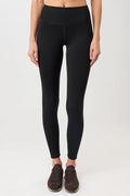 Person von vorne in einer schwarzen High-Rise-Leggings "Limitless" mit dynamischen Teilungsnähten und dunklen Sneakern vor hellem Hintergrund.