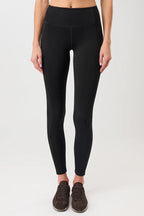 Person von vorne in einer schwarzen High-Rise-Leggings "Limitless" mit dynamischen Teilungsnähten und dunklen Sneakern vor hellem Hintergrund.