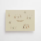 Postkarte "Dance" im DIN-A6-Format von Anna Cosma mit tanzenden, filigranen Figuren, kleinen Sternen und dem Text „Maybe it's all part of the dance...“ auf einem warmen, strukturierten Naturpapier-Hintergrund.